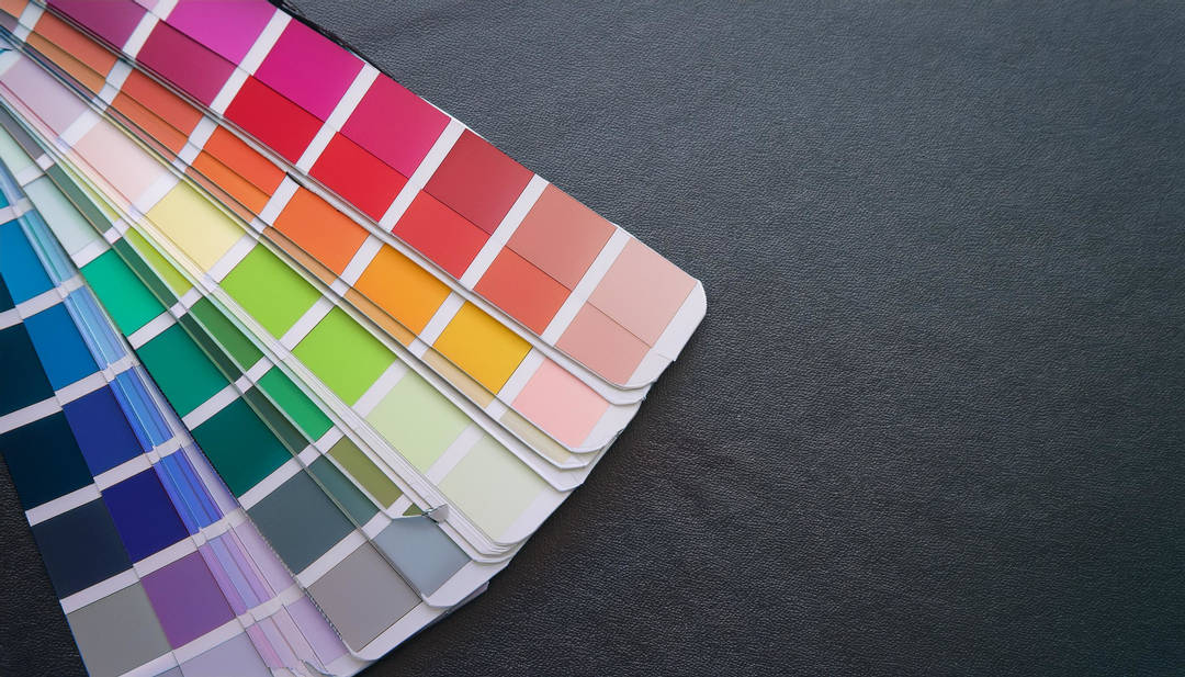 Värikarttojen kokoelma levitettynä tummanharmaalla pinnalla, joka sisältää eri värisävyjä kuten punaisia, sinisiä, vihreitä ja oransseja.