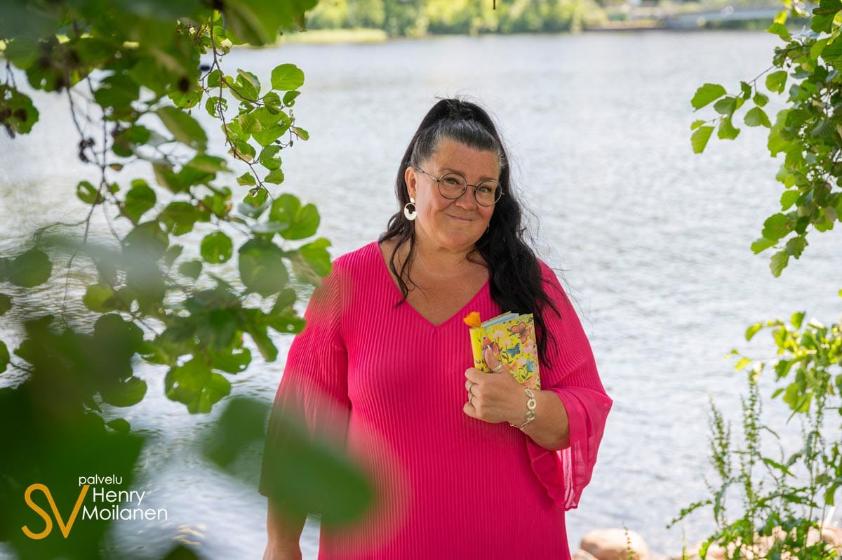 Jarna Pihlajamäki hymyilee järven rannalla katsoen kameraan.